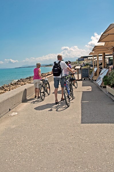 Turisti con la bicicletta di fronte alla fila dei ristoranti vivini al porto. 
