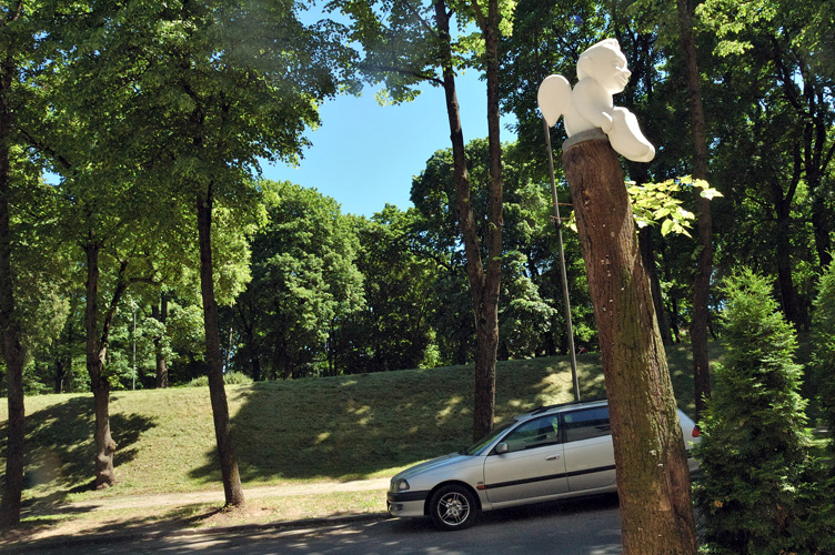Un candido angelo se ne sta seduto su tronco d'albero, vicino al parco.