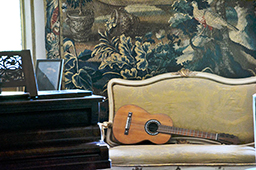 Veduta della sala della musica, con pianoforte e chitarra.