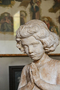 scultura di bambina a mani giunte.